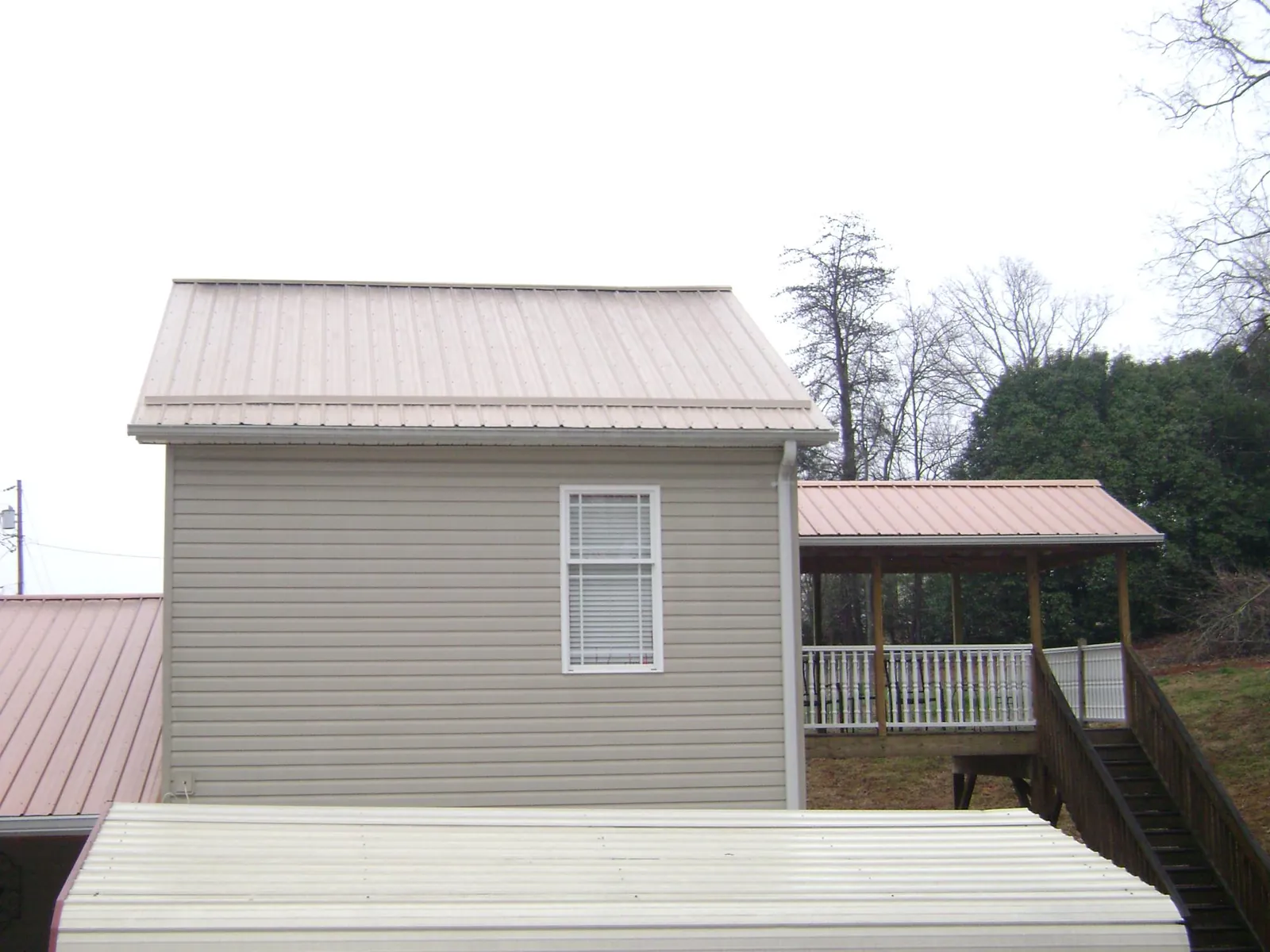 Tan metal roofs on a two story addition and attached porch, from a Roof Replacement job in Tacoma
