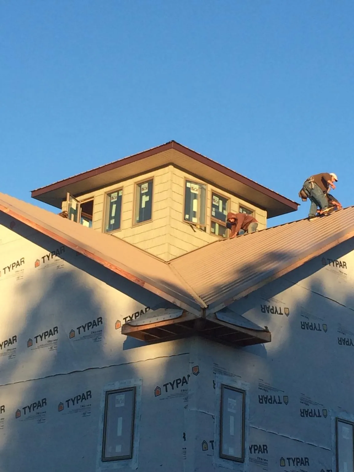 Roofers working around a rooftop cupola on a new metal roof at sunset — Roof Waterproofing in Tacoma by Roofing Brothers